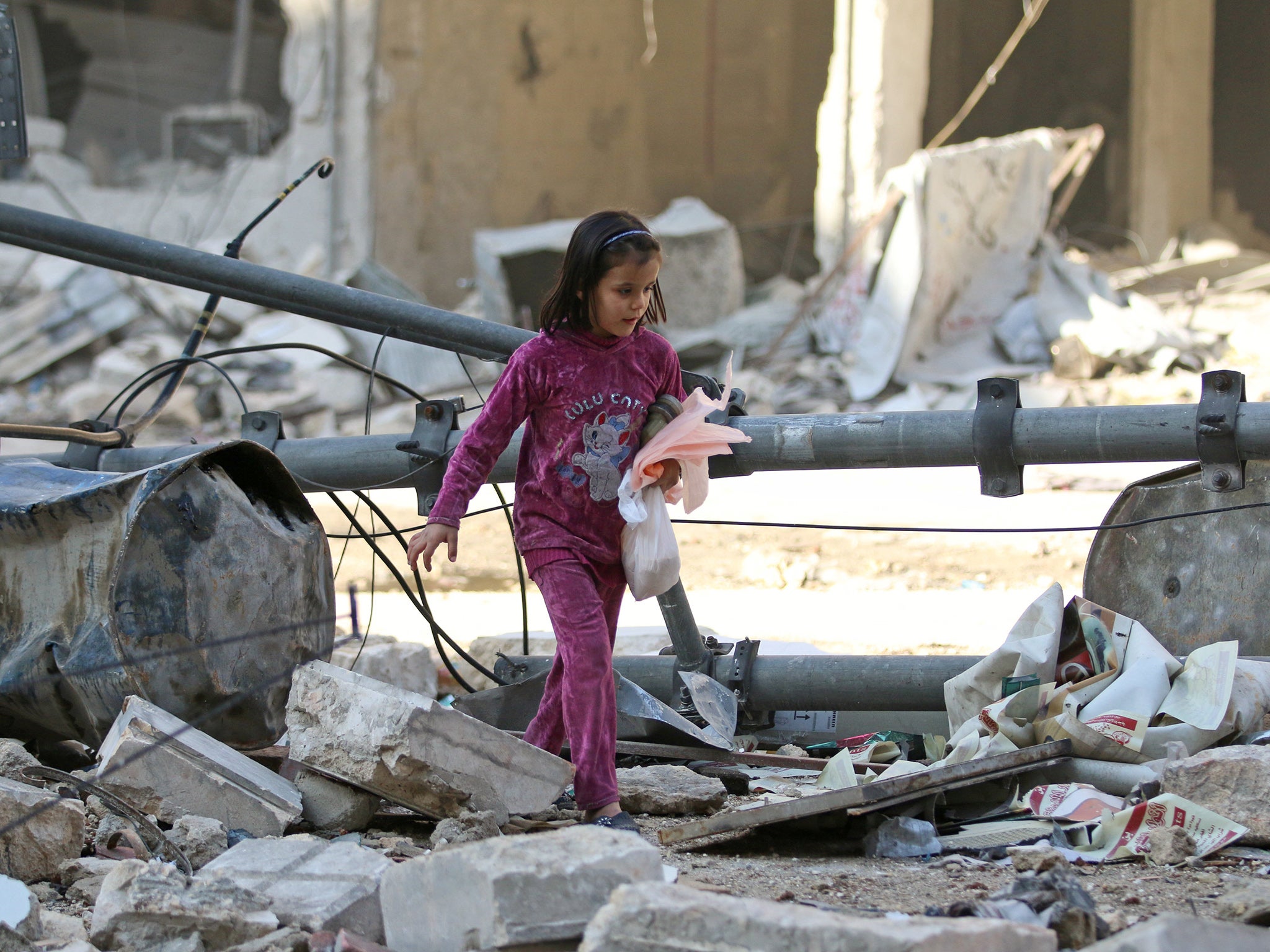 A young girl picks her way through the rubble of Aleppo