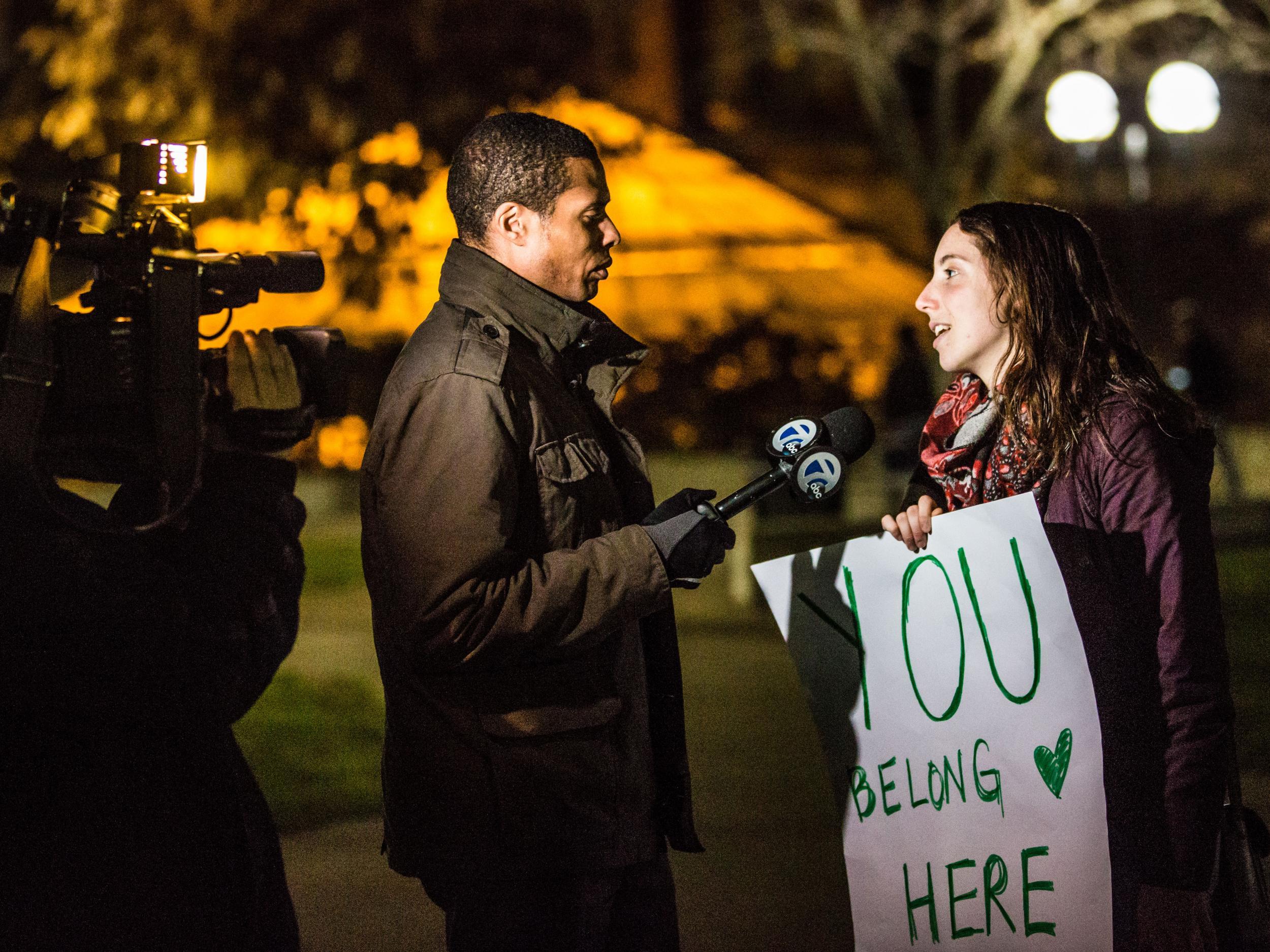 A woman carries a sign saying you belong here at a public prayer gathering held by Muslim students at Michigan University