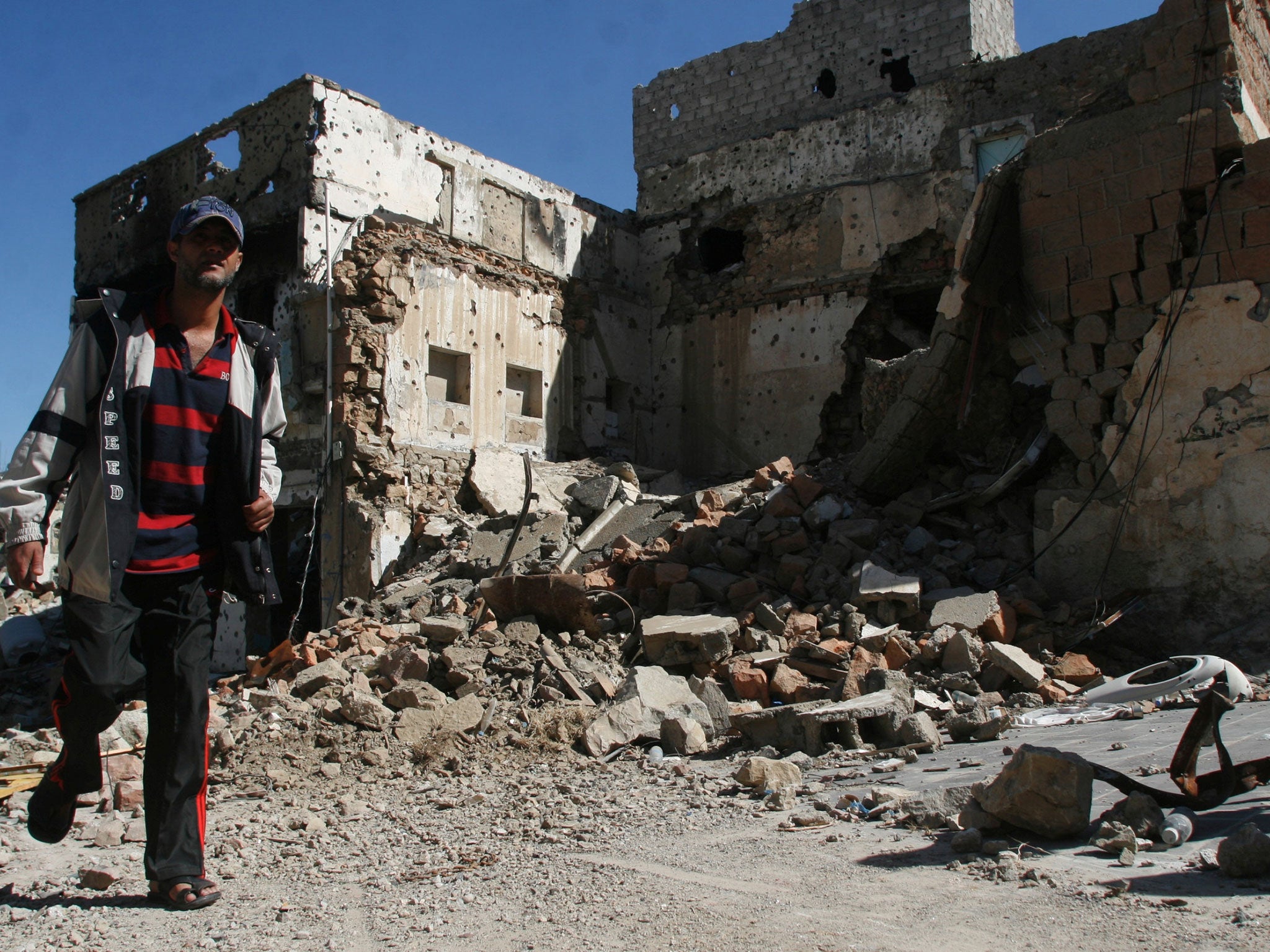 A man walks past a house destroyed during battles between Houthi fighters and pro-government fighters in the southwestern city of Taiz, Yemen November 17, 2016.