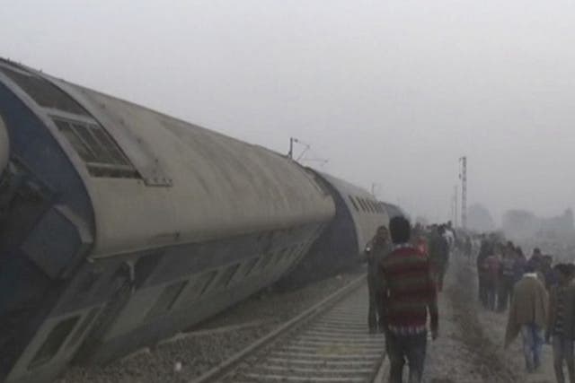 People gather at the site of a train accident near Pukhrayan