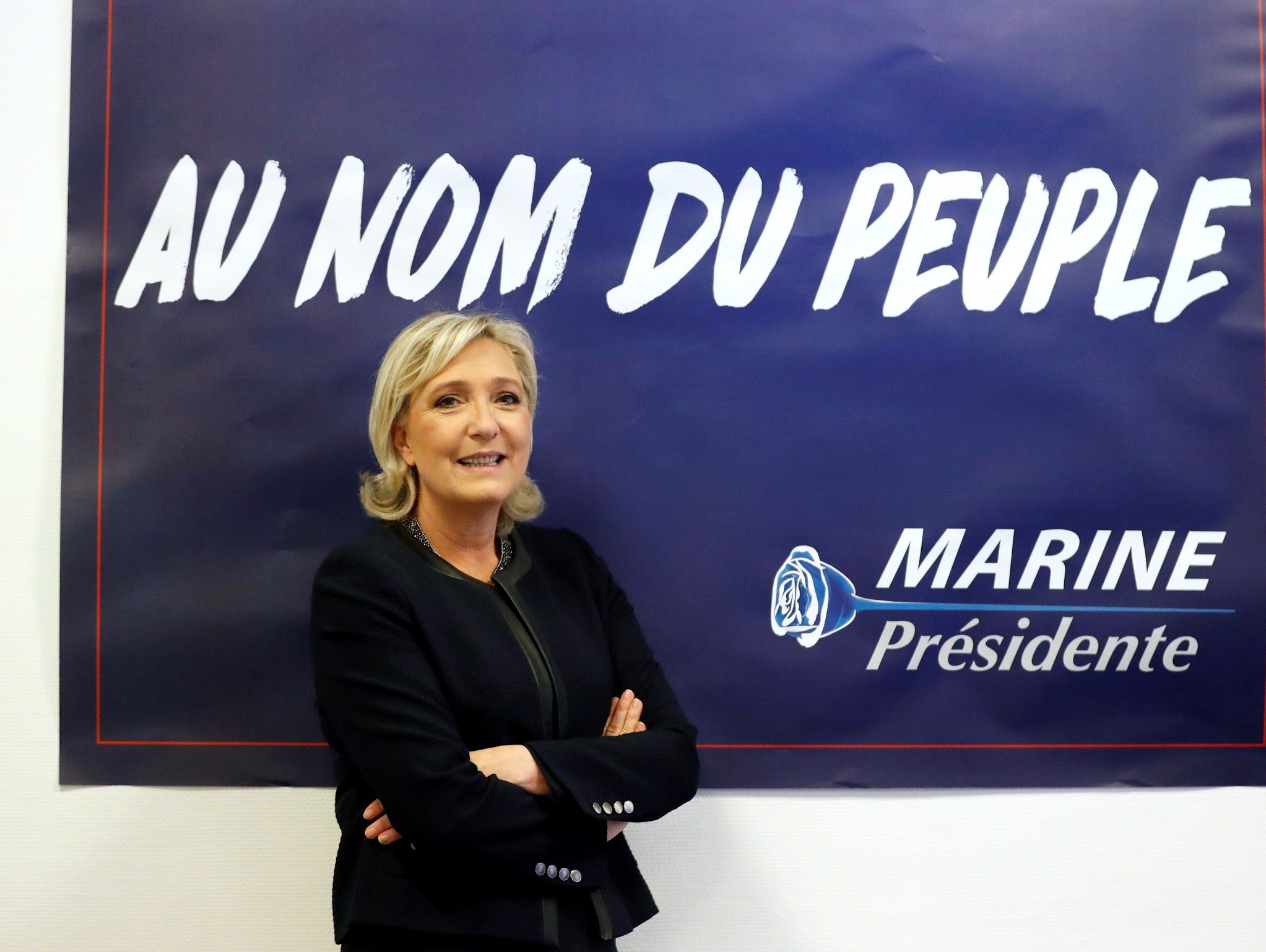 France's far-right National Front (FN) leader Marine Le Pen poses in front of a poster for her 2017 French presidential election campaign