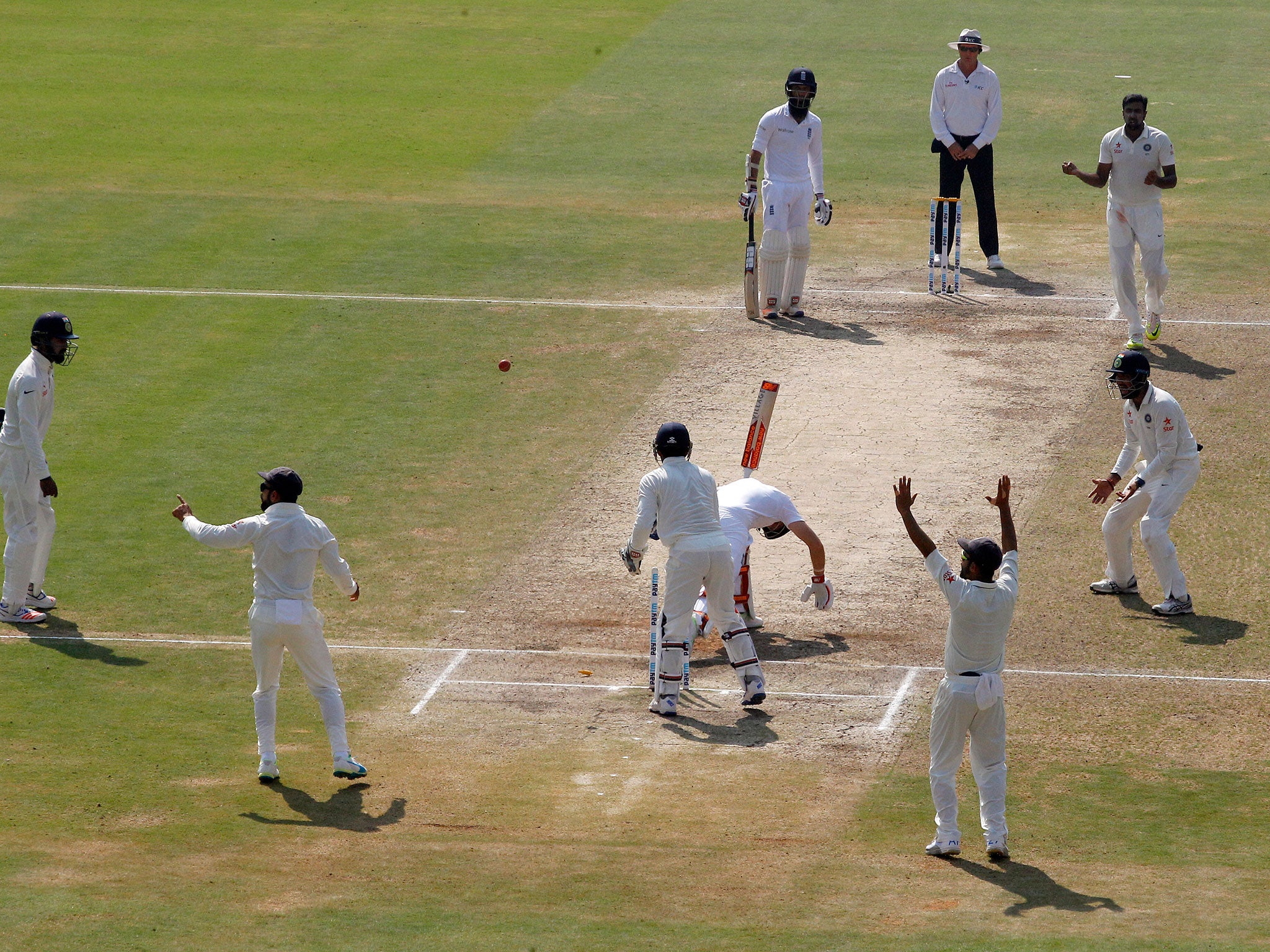 India's Ravichandran Ashwin, without a cap top right, and teammates react as England's Joe Root plays a shot.