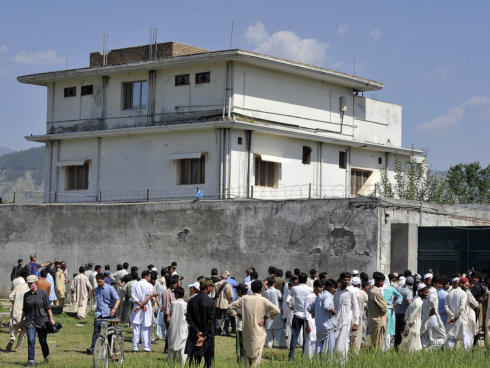 Pakistani media and local residents gather outside the hideout of Osama bin Laden following his death by US special forces in 2011