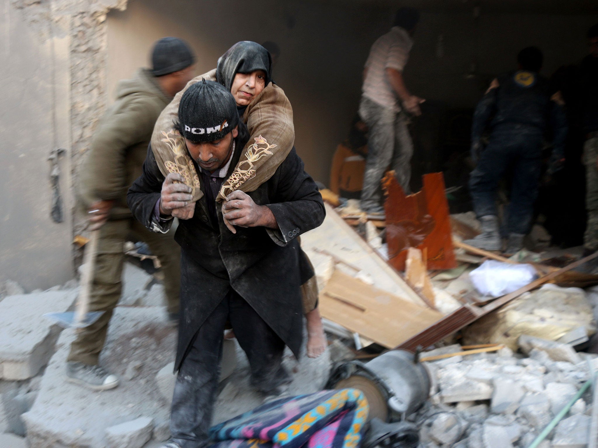 A Syrian rescuer carries a woman who was rescued the rubble of a building following reported air strikes on Aleppo’s rebel-held district of al-Hamra on Sunday