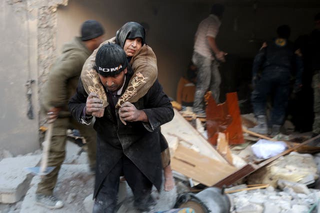 A Syrian rescuer carries a woman who was rescued the rubble of a building following reported air strikes on Aleppo's rebel-held district of al-Hamra on November 20, 2016.