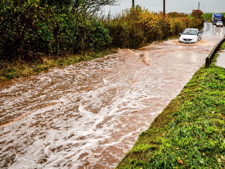 Cars creep through flood water on the main A396 between Tiverton and Exeter near, Upexe