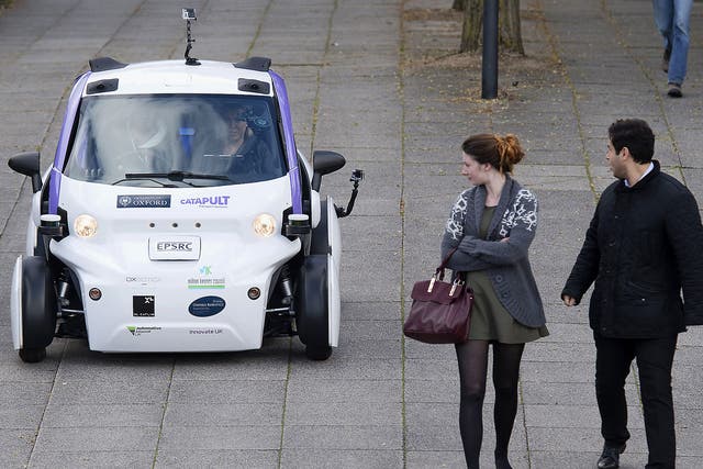 People look towards an autonomous self-driving vehicle, as it is tested in a pedestrianised zone, during a media event in Milton Keynes, UK