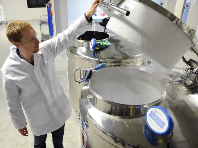 A technician opens a vat of liquid nitrogen, used in cryogenic freezing