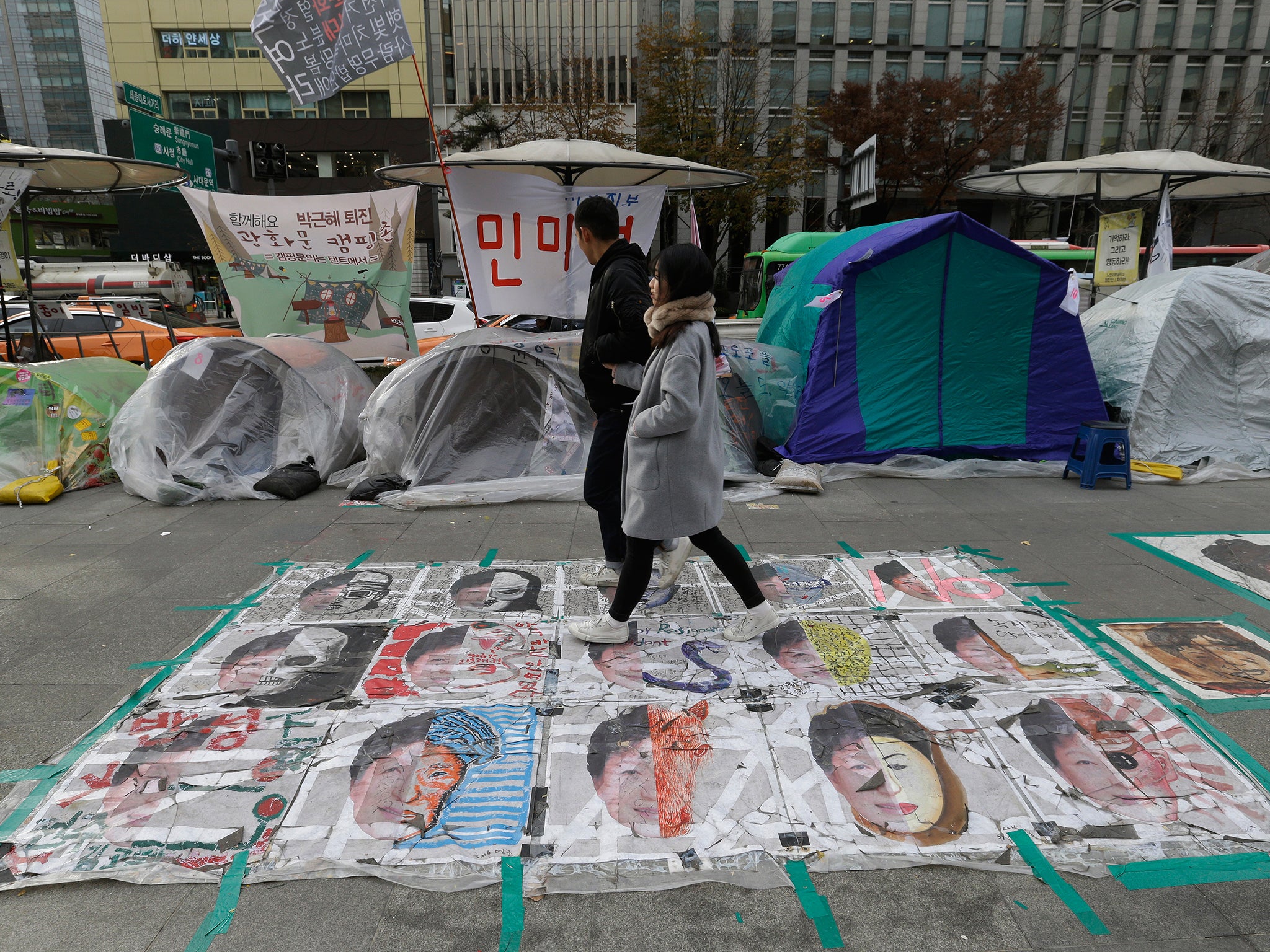 A couple walks on paintings criticizing South Korean President Park Geun-hye on a street in Seoul, South Korea