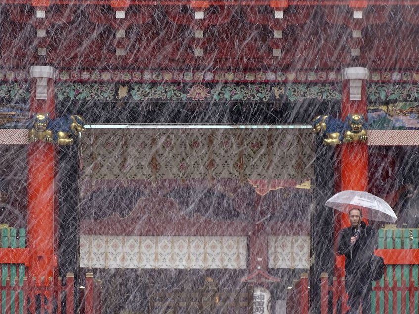 A man stands near the gate in the snow at Kanda Myojin shrine in Tokyo