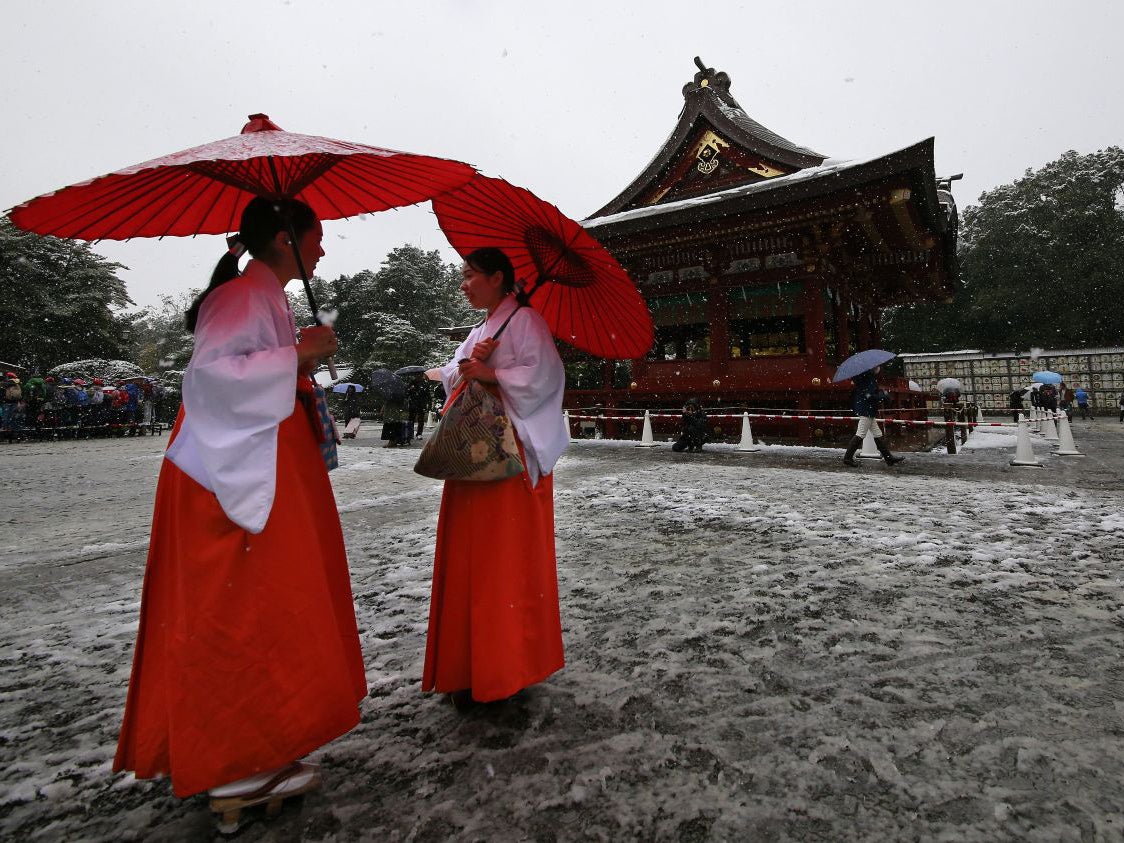 Shrine maidens chat in the snow at the Tsurugaoka Hachimangu Shrine in Kamakura, near Tokyo