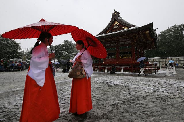 Shrine maidens chat in the snow at the Tsurugaoka Hachimangu Shrine in Kamakura, near Tokyo