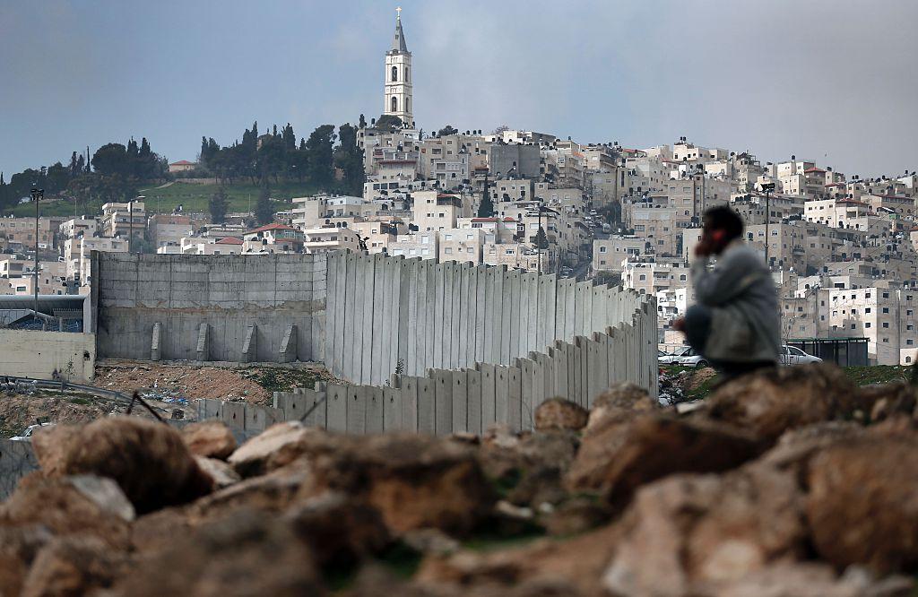 A Palestinian man sits near Israel’s controversial separation barrier