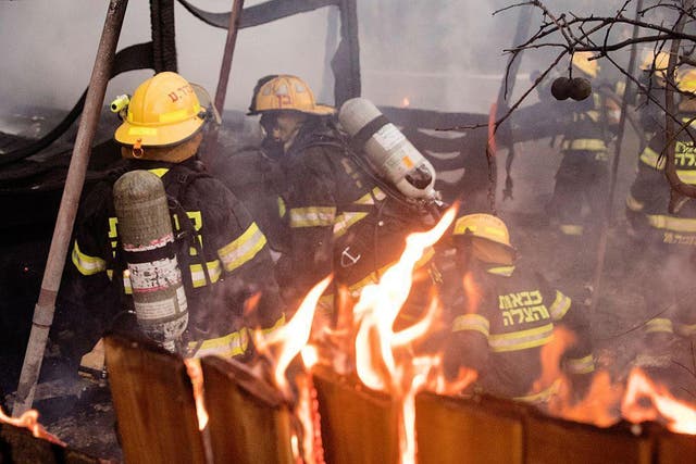 Israeli firefighters help extinguish a fire in the northern port city of Haifa on Thursday