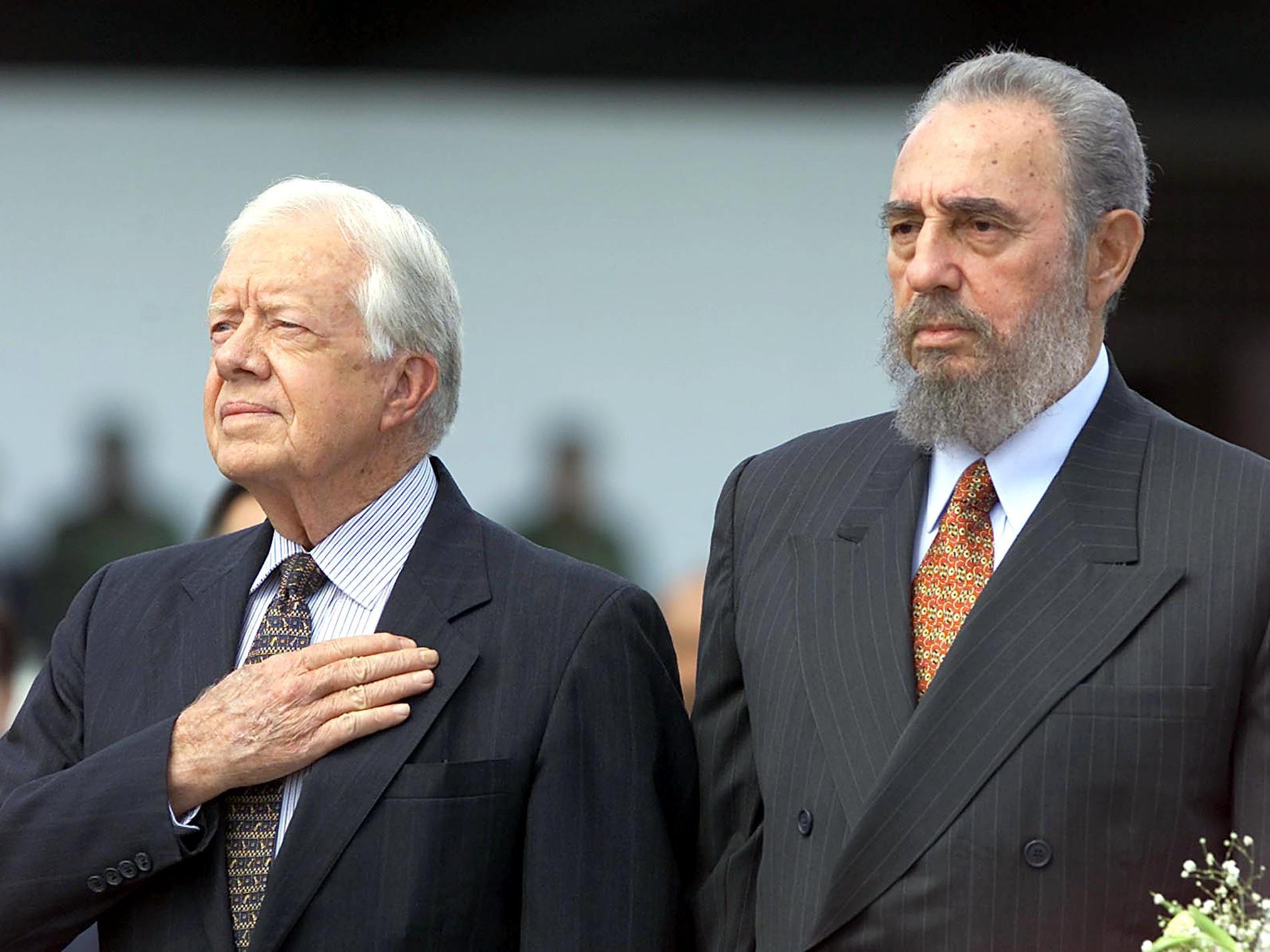 Former US president Jimmy Carter (L) and Cuban President Fidel Castro listen to US National Anthems after Carter's arrival at the Jose Marti airport in Havana 12 May 2002