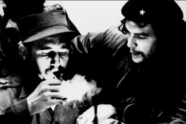 <p>This file photo taken in the 1960s shows then-Cuban prime minister Fidel Castro lighting a cigar while listening to Che Guevara</p>