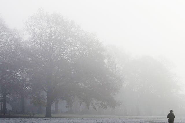 A man walks his dog through the fog in a Park in Knutsford, Cheshire