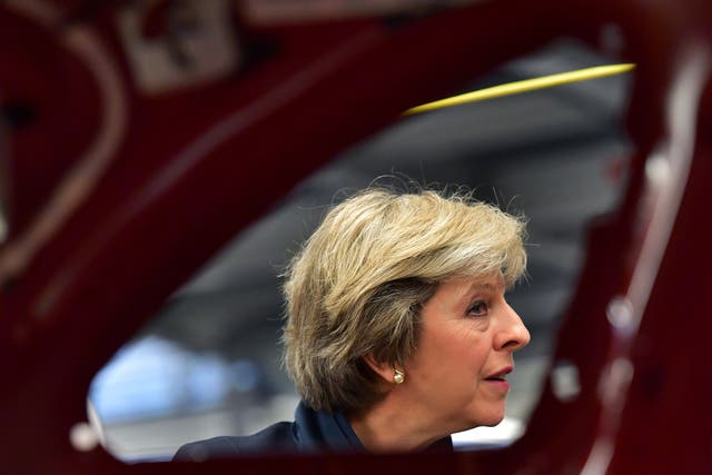 Theresa May views a car on a production line during a visit to the Jaguar Land Rover factory
