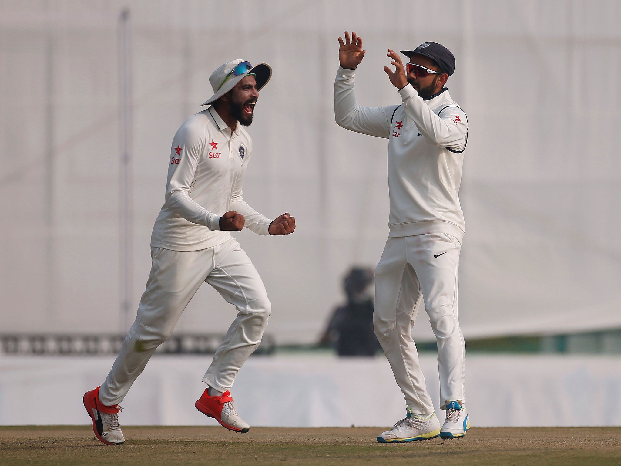 India's Virat Kohli and Ravindra Jadeja (L) celebrate the dismissal of England's Jos Buttler