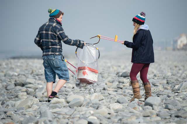 Two young student volunteers cleaning rubbish off the beach, Borth Ceredigion Wales UK