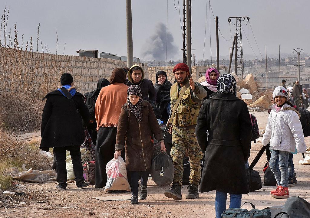 Members of Syrian government forces assist families fleeing from east Aleppo heading to the government-controlled west side of the city on November 29, 2016