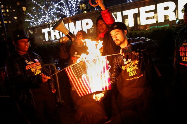 Supporters of the 'NYC Revolution Club' burn the US flag outside the Trump International Hotel and Tower