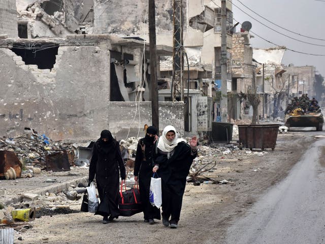 Syrian residents fleeing the eastern part of Aleppo walk through a street in Masaken Hanano, a former rebel-held district which was retaken by the regime forces last week, on November 30, 2016