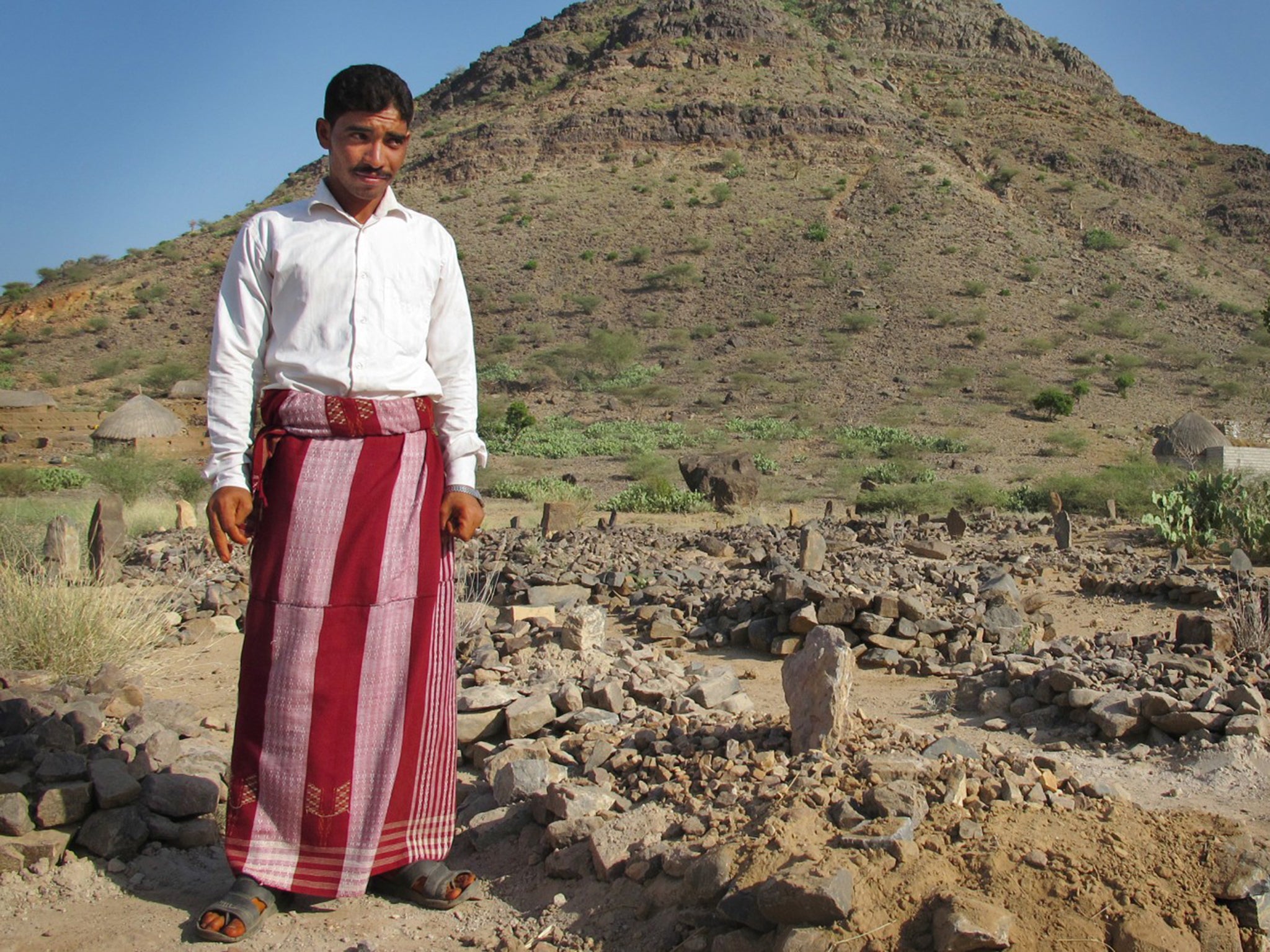 Abdul Fatah Baashami stands next to grave of his only child, Nabil, who died of hunger. He was 14 months old