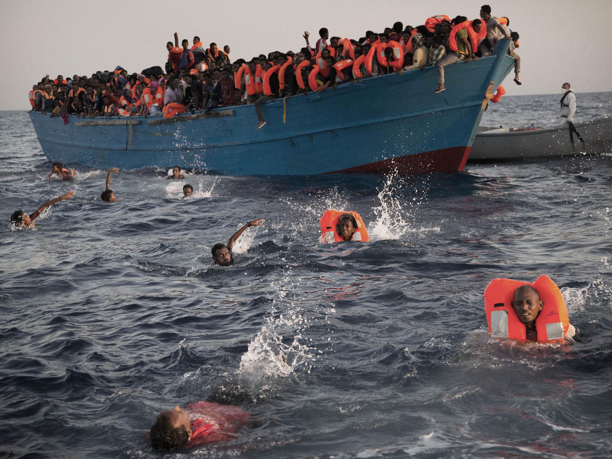 Refugees jump into the water from a crowded wooden boat as they are helped during a rescue operation in the Mediterranean Sea, around 13 miles (20 kilometres) north of Sabratha, Libya, 29 August, 2016