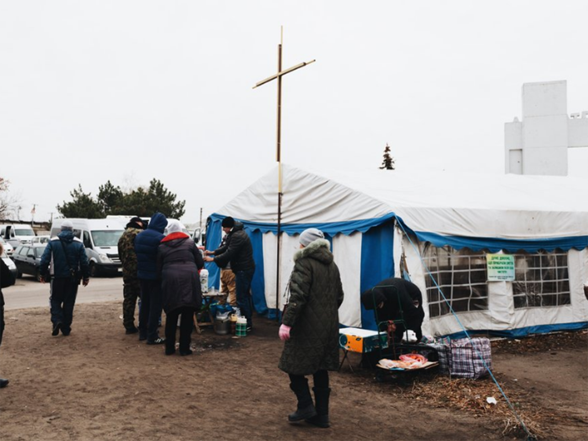 Members crowd outside one of the church’s tents, where services are often held