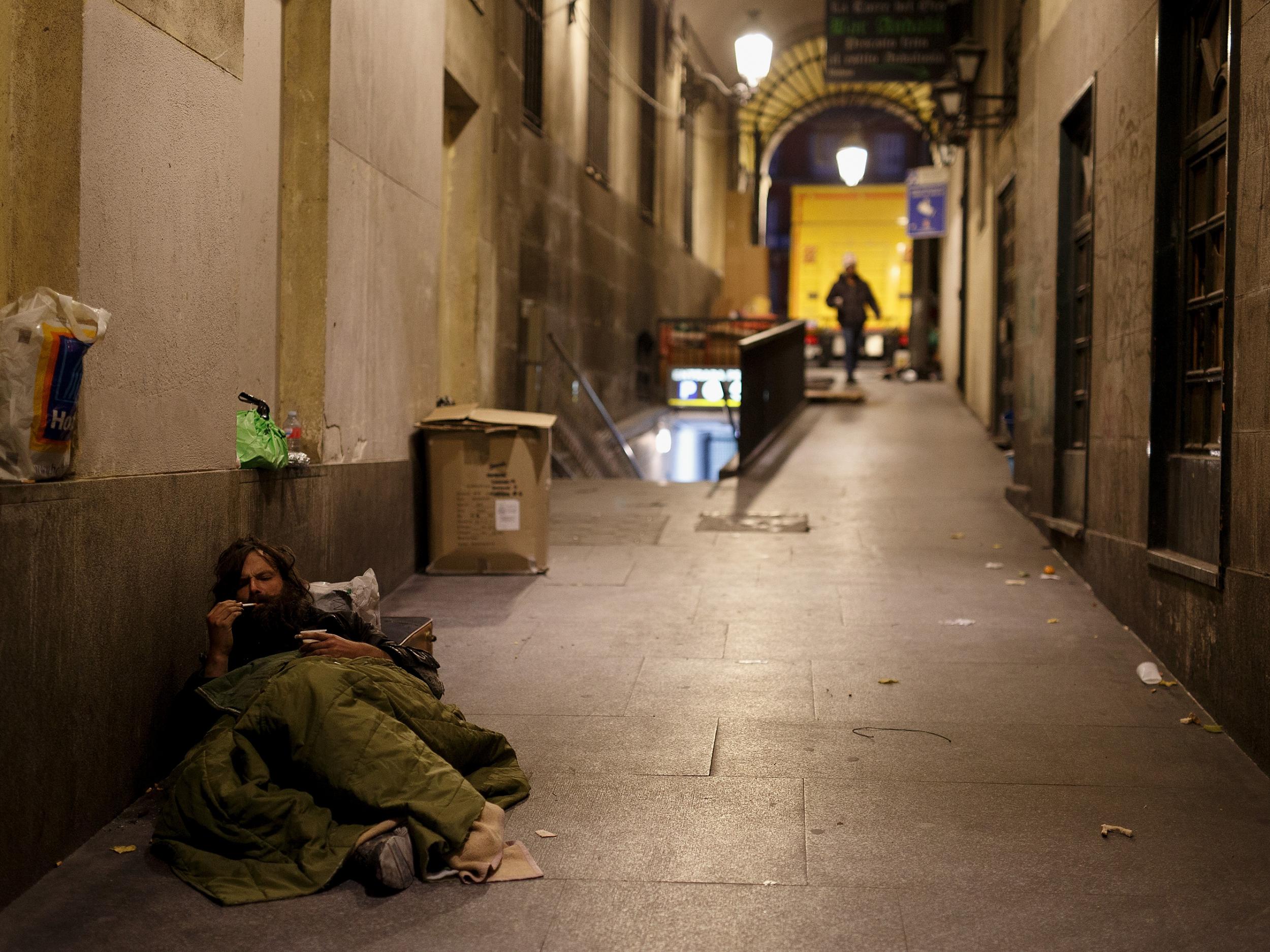 A homeless man rests in the street in Madrid