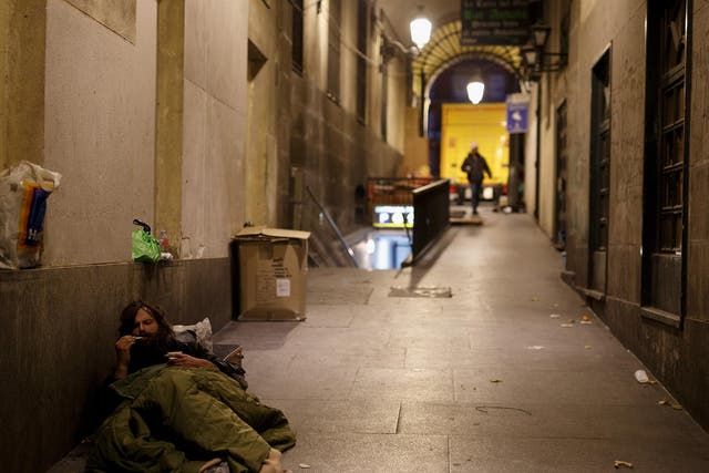 A homeless man rests in the street in Madrid
