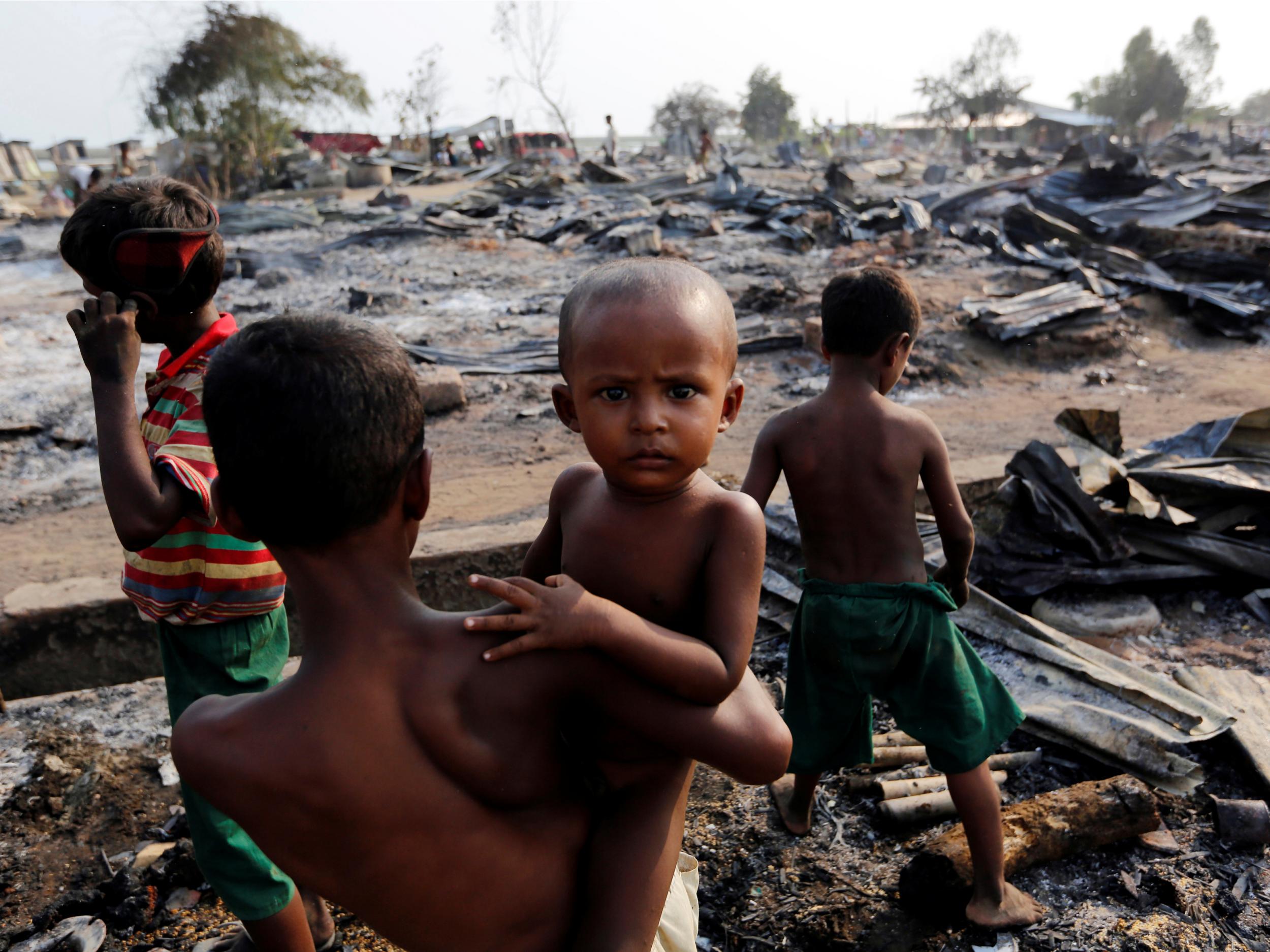 Boys stand among debris after fire destroyed shelters at a camp for internally displaced Rohingya Muslims in the western Rakhine State