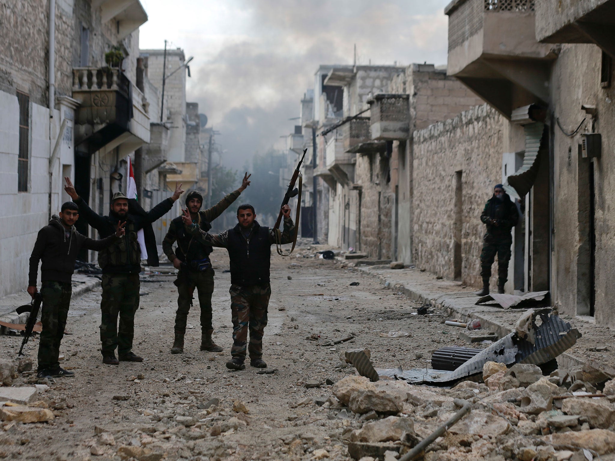 Syrian army soldiers flash the victory as they patrol the east Aleppo neighborhood of Tariq al-Bab, Syria, on 3 December