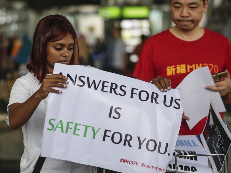 Malaysian Grace Subathirai Nathan (L), whose mother Anne Daisy was on board flight MH370, holds a banner with next-of-kin Jiang Hui of China