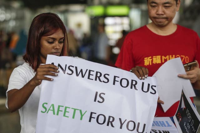 Malaysian Grace Subathirai Nathan (L), whose mother Anne Daisy was on board flight MH370, holds a banner with next-of-kin Jiang Hui of China