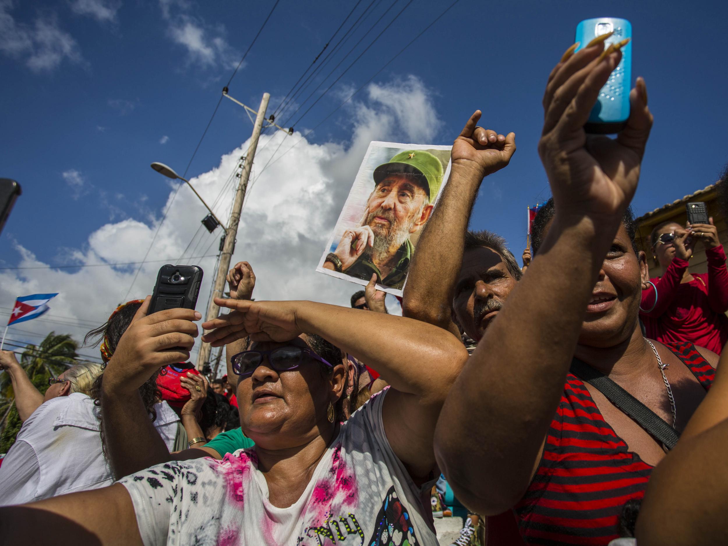 People watch the funeral procession carrying the ashes of Fidel Castro past Moncada Fort in Santiago