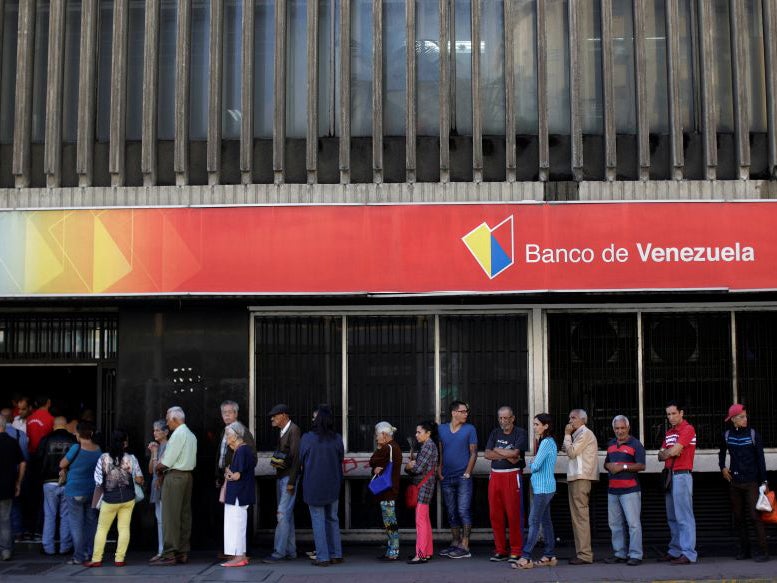 People line up to withdraw cash from a Banco de Venezuela branch in Caracas, Venezuela