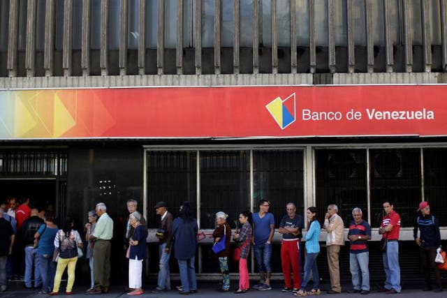 People line up to withdraw cash from a Banco de Venezuela branch in Caracas, Venezuela
