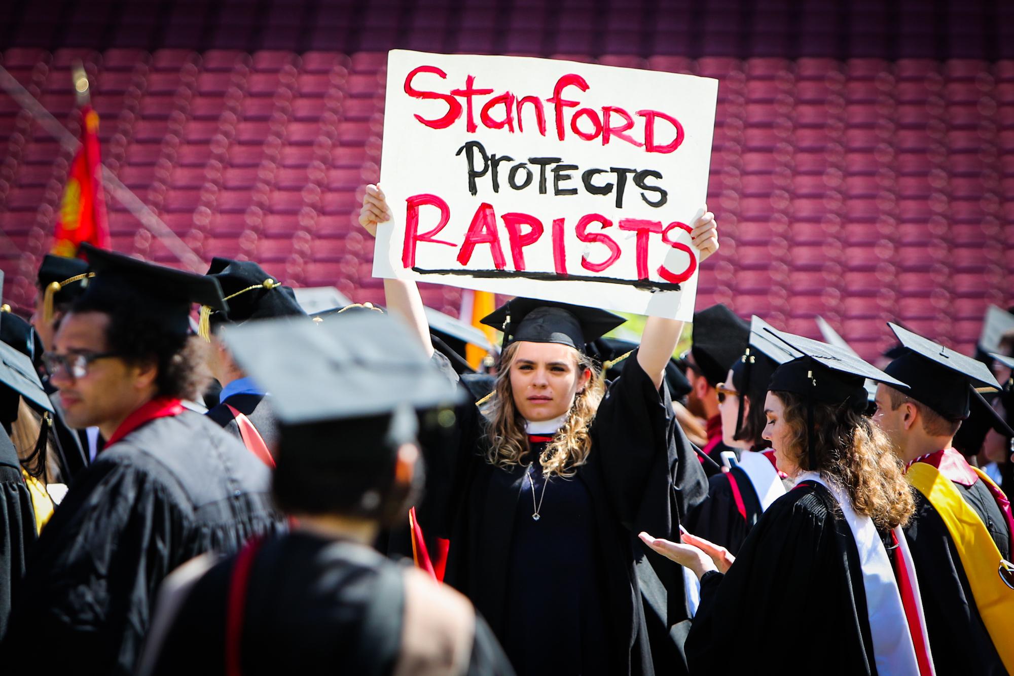 A woman carries a sign in solidarity for a Stanford rape victim during graduation at Stanford University, in Palo Alto, California, on June 12, 2016. Stanford students are protesting the university's handling of rape cases alleging that the campus keeps secret the names of students found to be responsible for sexual assault and misconduct.