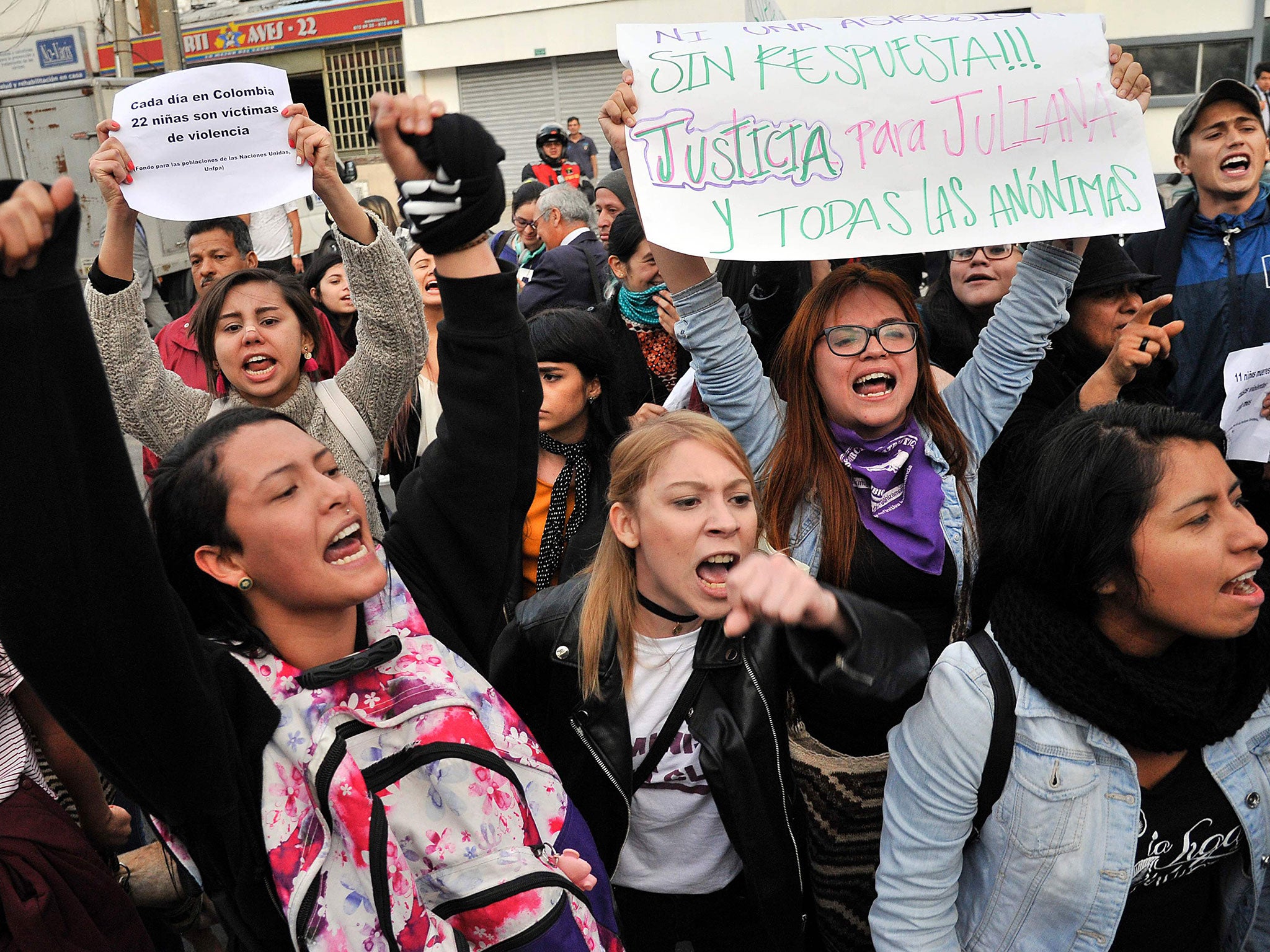 People protest as riot police transfer the alleged murderer of a seven-year-old girl from the clinic where he was being treated for a cocaine overdose to court, in Bogota, on 6 December