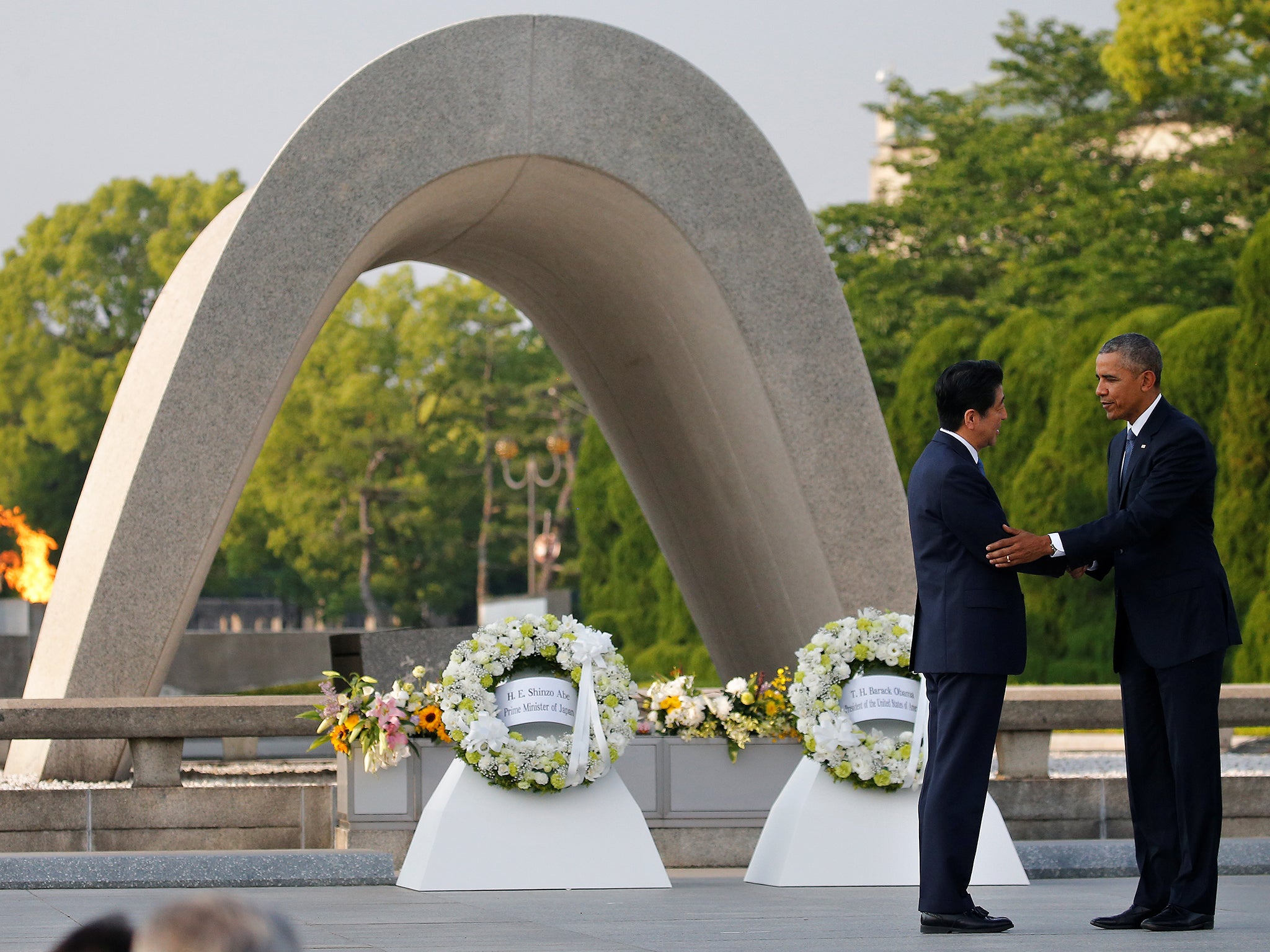 US President Barack Obama puts his arm around Japanese Prime Minister Shinzo Abe after they laid wreaths in front of a cenotaph at Hiroshima Peace Memorial Park in Japan on May 27 2016