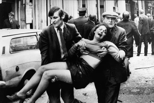 An injured girl is carried after a terrorist bomb exploded in a car parked in a busy shopping street in 1970s Belfast