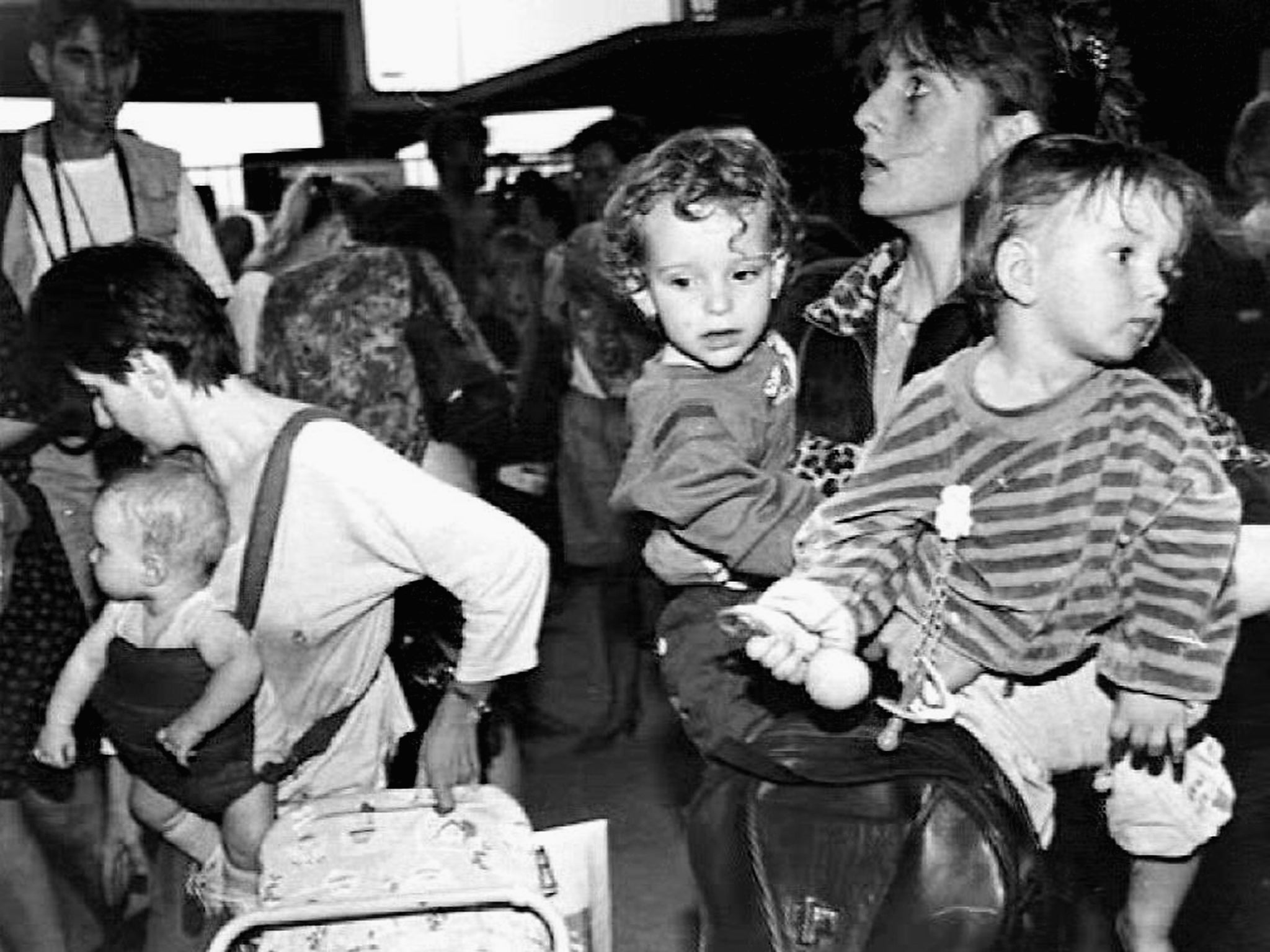 A Bosnian mother carries her children after fleeing from Sarajevo in August 1992