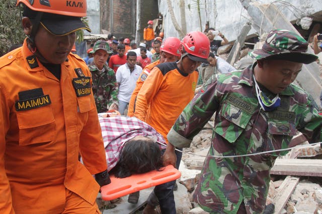 Indonesian rescue workers carry a survivor from a fallen building after an earthquake in Ulee Glee, Pidie Jaya, in the northern province of Aceh