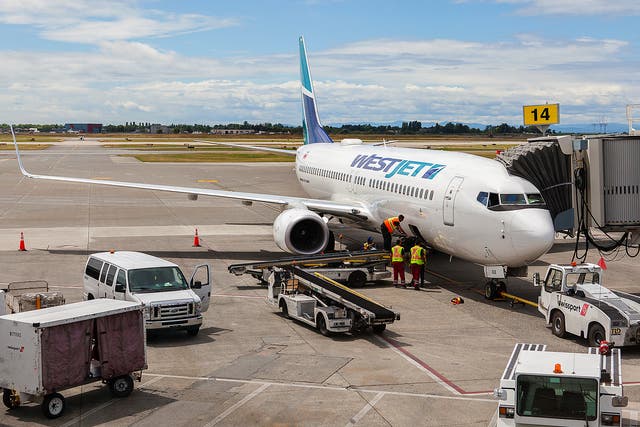 <p>Westjet Airplane parked at a terminal at Vancouver International Airport</p>