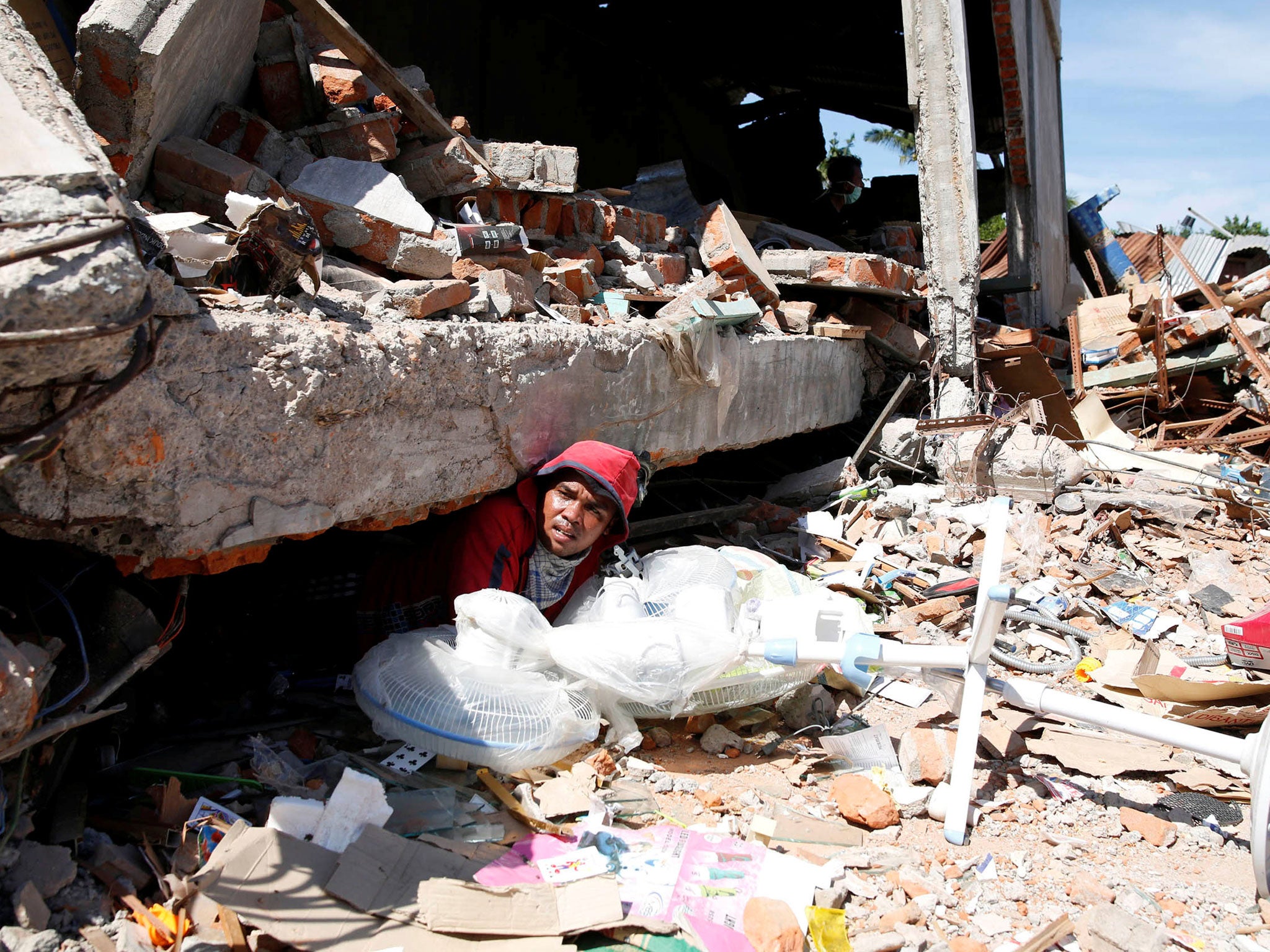 A man retrieves fans from a collapsed shop following a strong earthquake in Meureudu, Pidie Jaya