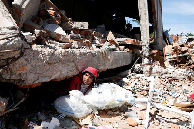 A man retrieves fans from a collapsed shop following a strong earthquake in Meureudu, Pidie Jaya