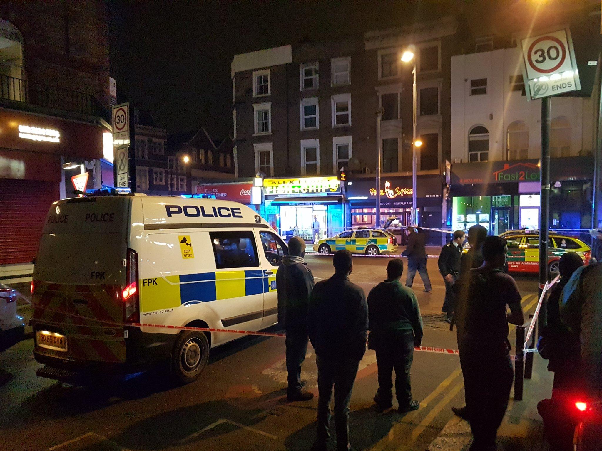 Bystanders look on after a shooting in Kilburn