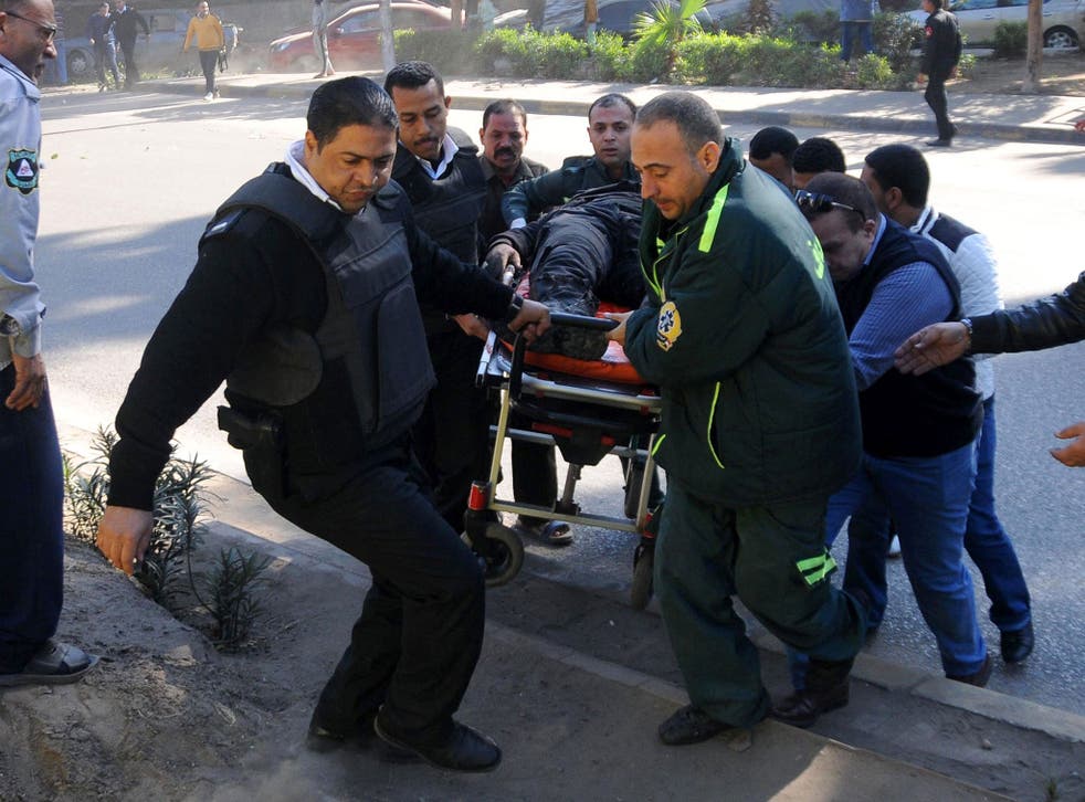 Egyptian emergency services carry a wounded victim at the site of a bomb attack next to a police checkpoint in the western Talibiya district of the capital Cairo on 9 December